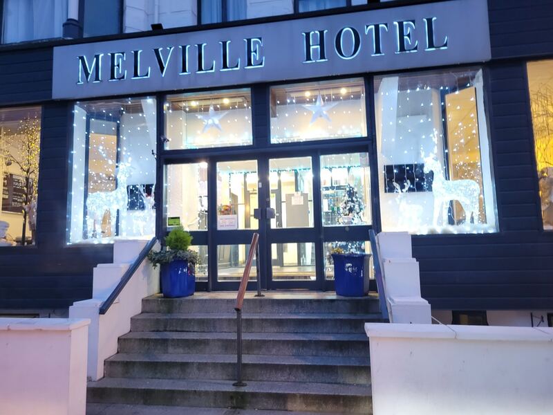 The Melville Hotel entrance at dusk, decorated with Christmas lights and illuminated reindeer.